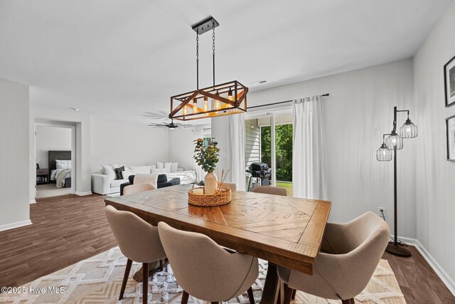 dining area featuring a chandelier, dark wood finished floors, and baseboards