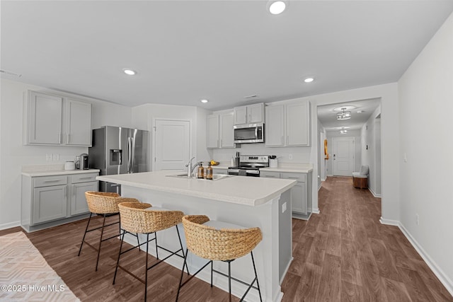 kitchen featuring a kitchen breakfast bar, dark wood-style flooring, appliances with stainless steel finishes, and a sink