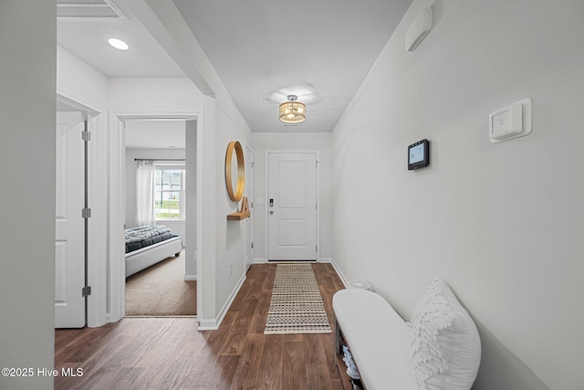 hallway with visible vents, wood finished floors, and baseboards