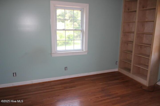 spare room with baseboards, a healthy amount of sunlight, and wood finished floors