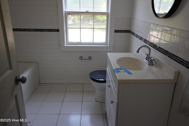 full bath featuring vanity, toilet, tile walls, a bath, and tile patterned floors