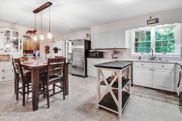 720 Swains Mill Rd, Harrellsville, NC 27942 - kitchen featuring freestanding refrigerator, white cabinets, a sink, hanging light fixtures, and glass insert cabinets