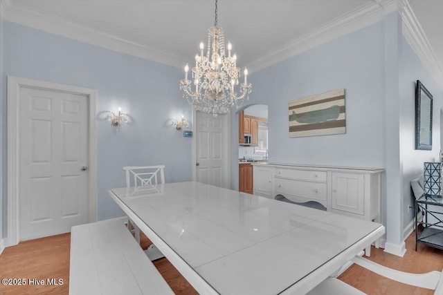 3720 Island Dr, North Topsail Beach, NC 28460 - dining room featuring crown molding, a notable chandelier, arched walkways, light wood-style flooring, and baseboards