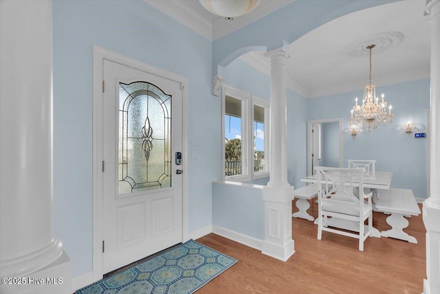 3720 Island Dr, North Topsail Beach, NC 28460 - entryway featuring crown molding, an inviting chandelier, light wood-style floors, arched walkways, and ornate columns