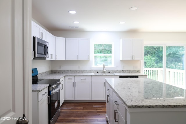 229 Spring Dr, Jacksonville, NC 28540 - kitchen featuring stainless steel microwave, range with electric stovetop, a sink, dark wood-type flooring, and white cabinets