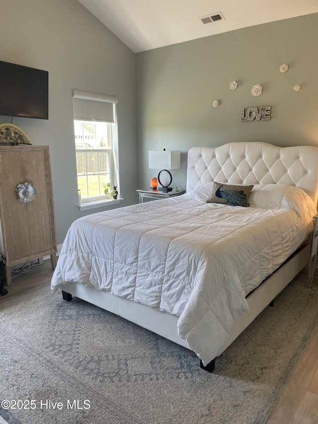 bedroom with visible vents, wood finished floors, and lofted ceiling