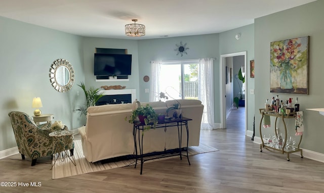 living area with baseboards, wood finished floors, and a chandelier