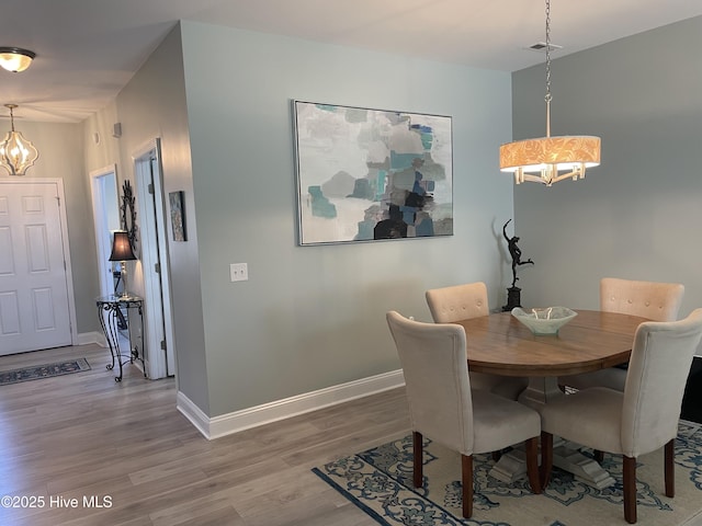 dining area featuring baseboards, a chandelier, wood finished floors, and visible vents