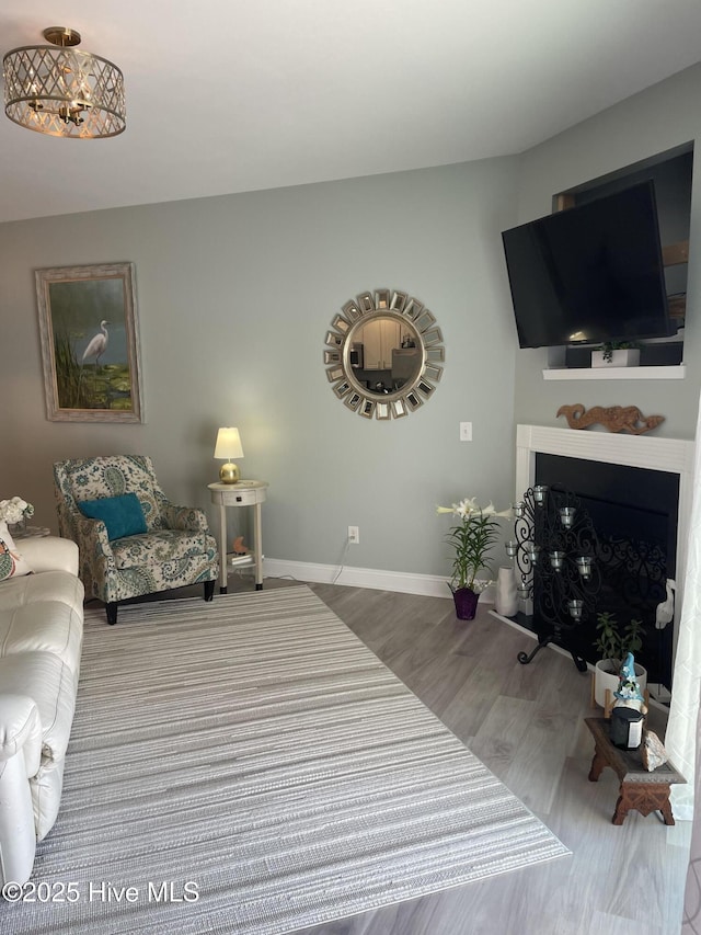 living area with baseboards, a fireplace, and wood finished floors