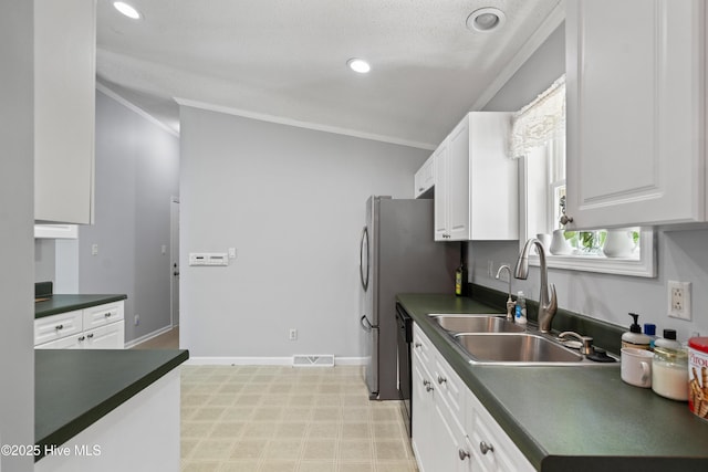 kitchen featuring white cabinets, a sink, dark countertops, ornamental molding, and light floors