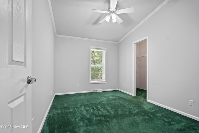 unfurnished bedroom featuring a spacious closet, carpet, ornamental molding, baseboards, and visible vents