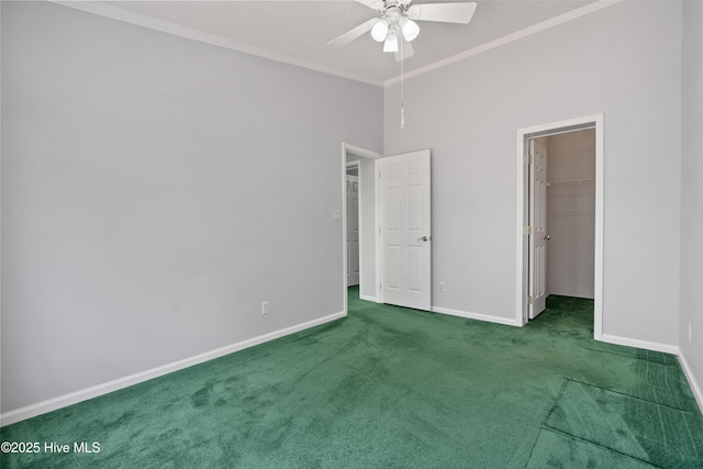 unfurnished bedroom with carpet floors, a spacious closet, crown molding, and baseboards
