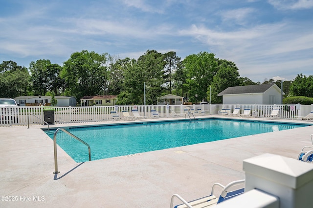 community pool featuring fence, an outbuilding, and a patio area