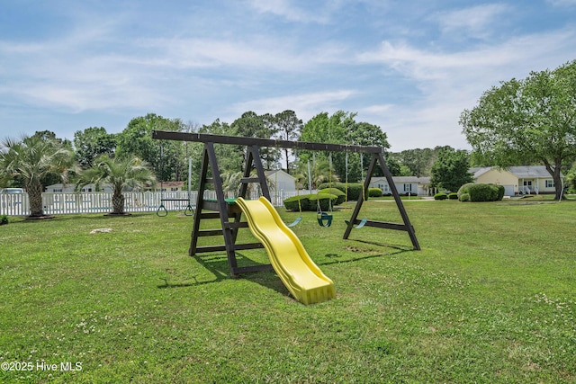 community jungle gym with a yard and fence