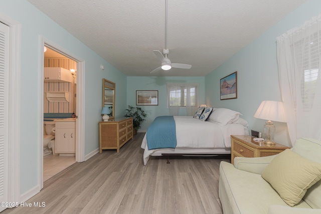 bedroom with ceiling fan, light wood finished floors, ensuite bath, a textured ceiling, and baseboards