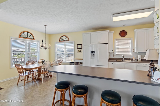 48 Wilmington St, Ocean Isle Beach, NC 28469 - kitchen with white appliances, dark countertops, a breakfast bar area, white cabinets, and a textured ceiling