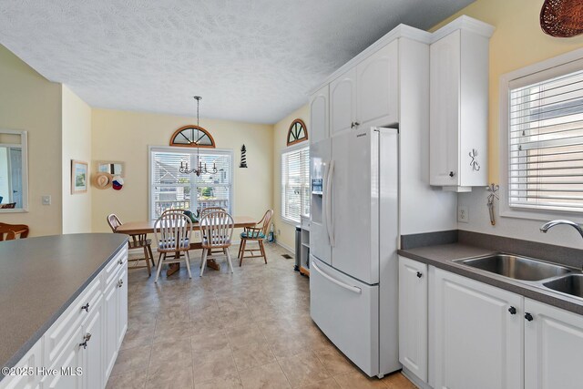 48 Wilmington St, Ocean Isle Beach, NC 28469 - kitchen with white refrigerator with ice dispenser, dark countertops, white cabinetry, and a textured ceiling