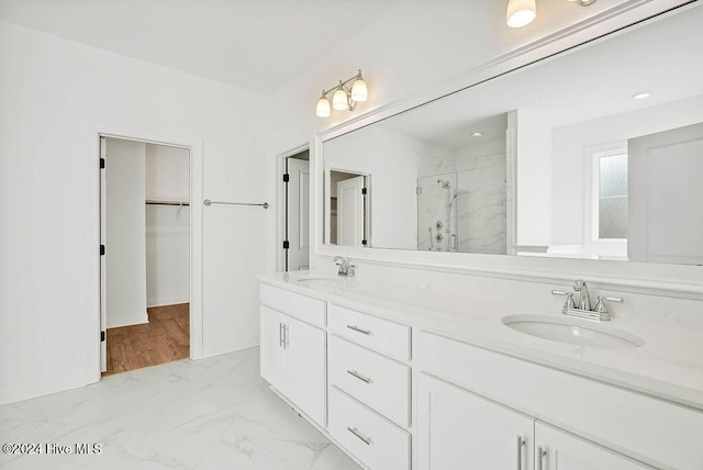 bathroom with double vanity, a sink, marble finish floor, a spacious closet, and a marble finish shower