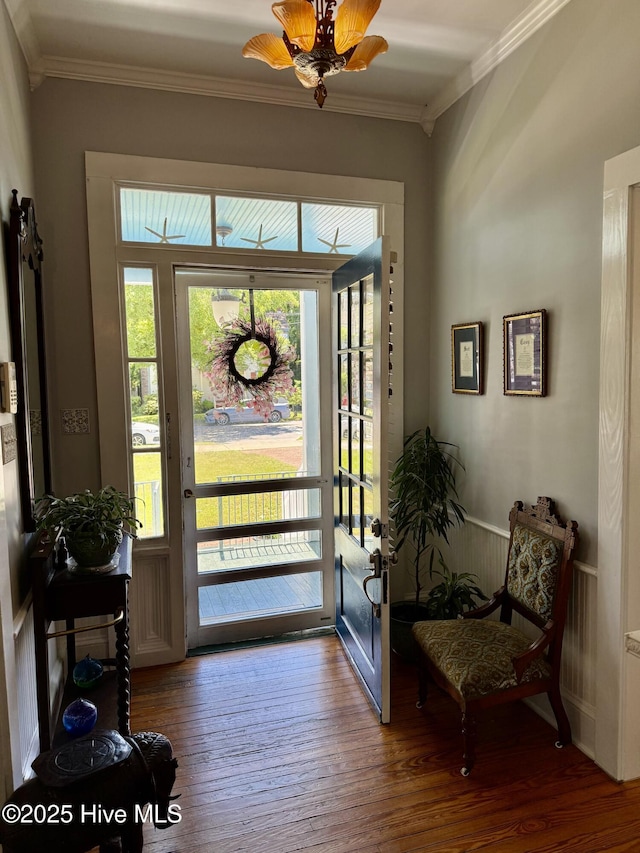 doorway to outside with ornamental molding and wood finished floors