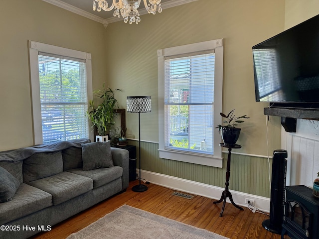 living area with crown molding, wood finished floors, a chandelier, and a wealth of natural light