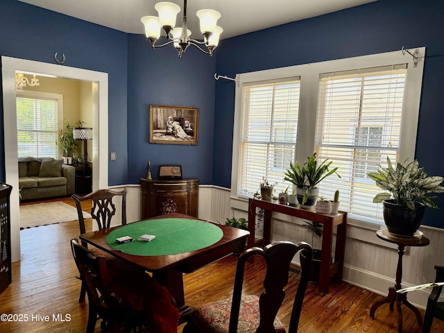 dining room with wainscoting, wood finished floors, and a notable chandelier