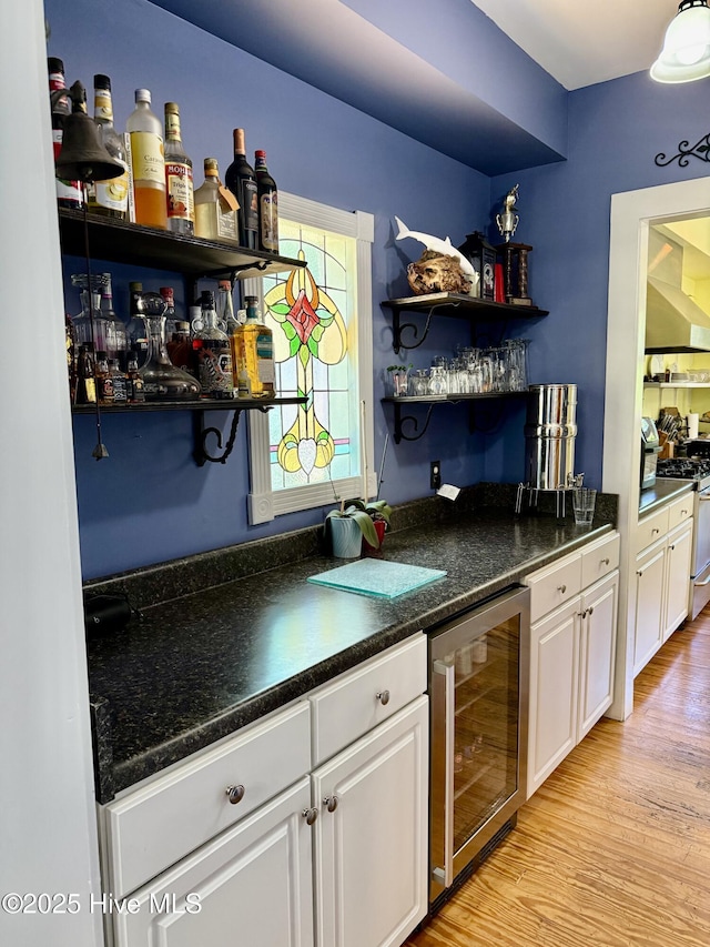 bar with light wood-style flooring, wet bar, wine cooler, and gas stove