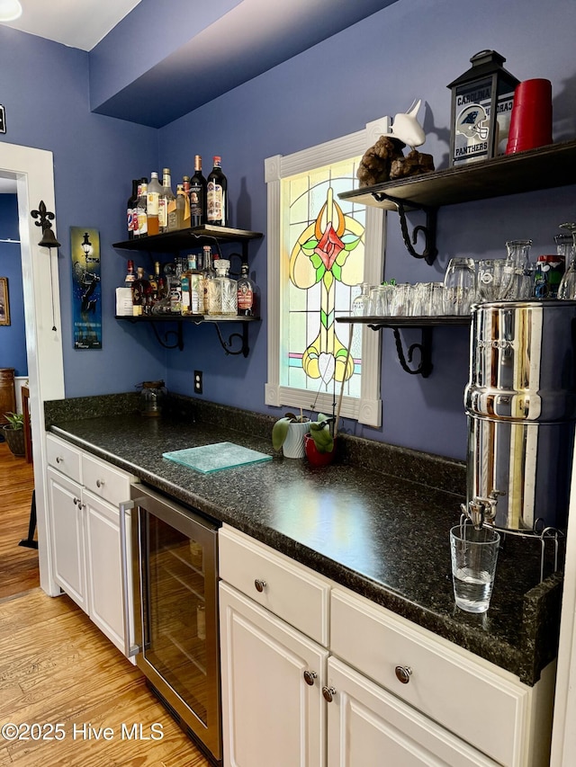 bar with light wood-type flooring, a bar, and wine cooler