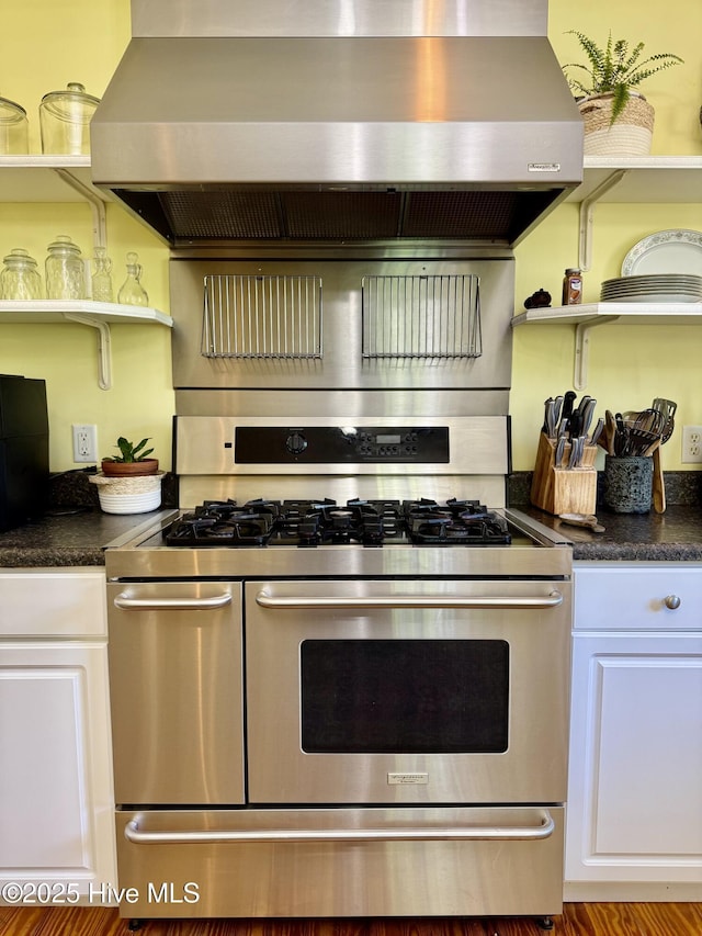 kitchen featuring dark countertops, open shelves, double oven range, and wall chimney exhaust hood