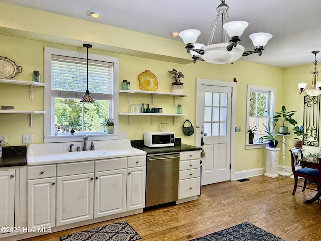 kitchen with white microwave, open shelves, a notable chandelier, and dishwasher