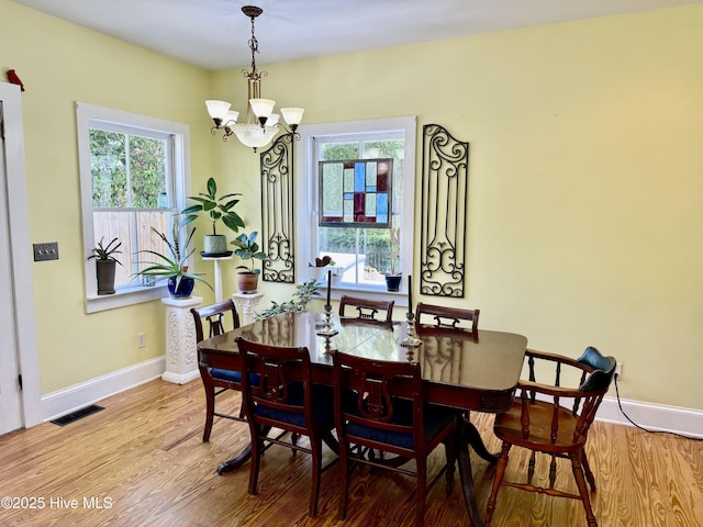 dining area with baseboards, a chandelier, wood finished floors, and visible vents