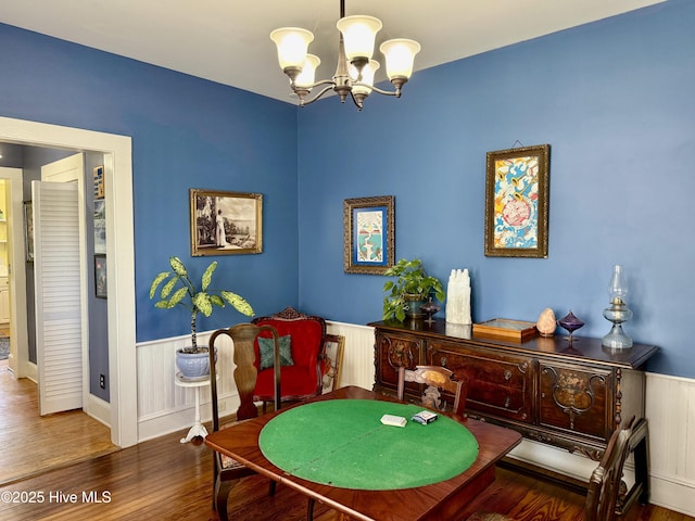 interior space with wainscoting, wood finished floors, and a chandelier