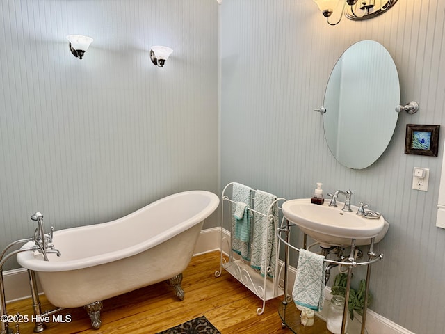 full bathroom featuring a sink, baseboards, a soaking tub, and wood finished floors