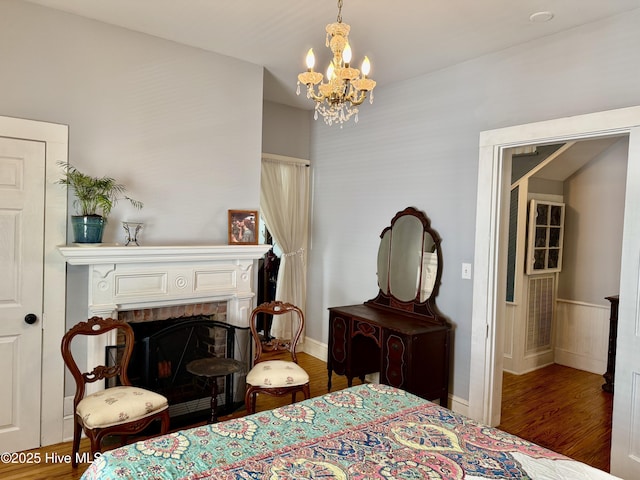 bedroom with an inviting chandelier, baseboards, a fireplace, and wood finished floors