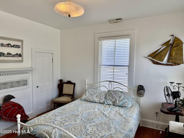 bedroom with baseboards, wood finished floors, and visible vents