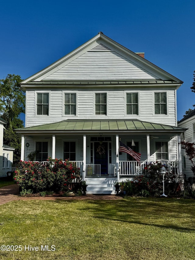 view of front facade with a standing seam roof, a front lawn, a porch, and metal roof