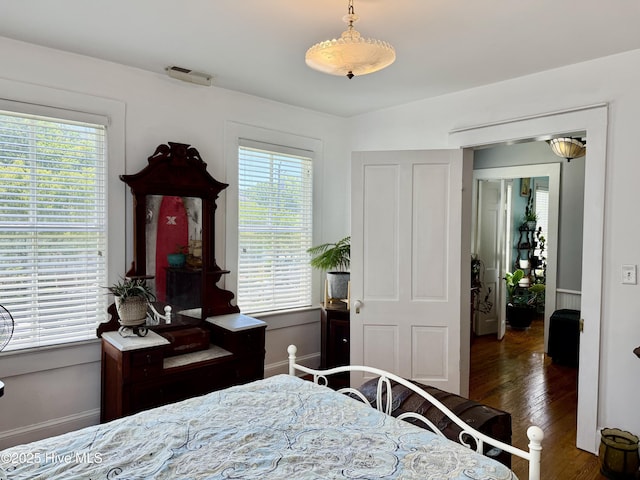bedroom featuring baseboards, multiple windows, wood finished floors, and visible vents