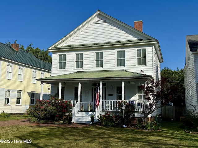 view of front of property with a porch, a chimney, and a front lawn