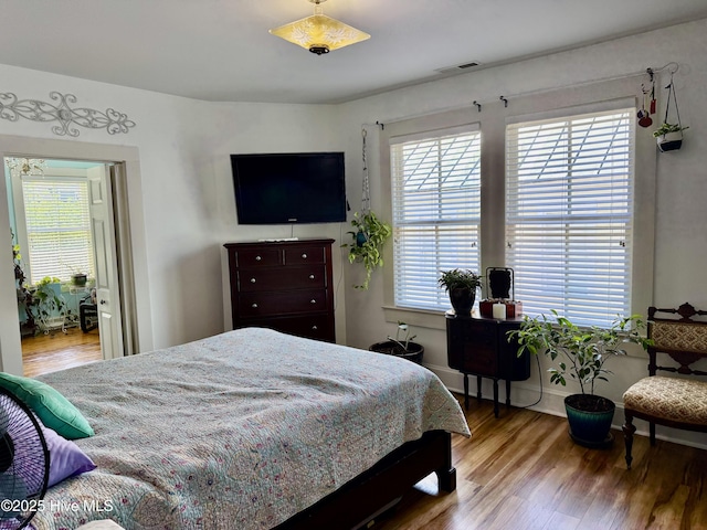 bedroom with visible vents, multiple windows, and wood finished floors