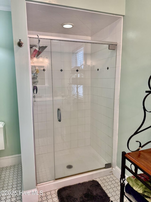 bathroom with baseboards, a shower stall, and tile patterned floors