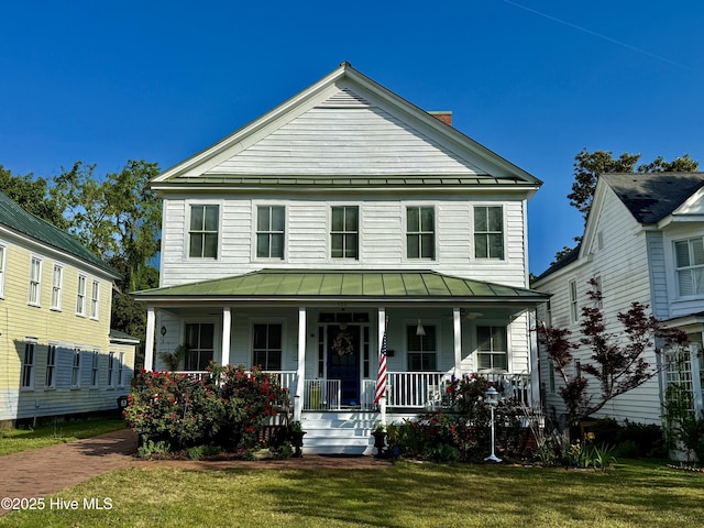 view of front of property with covered porch, a standing seam roof, metal roof, and a front lawn
