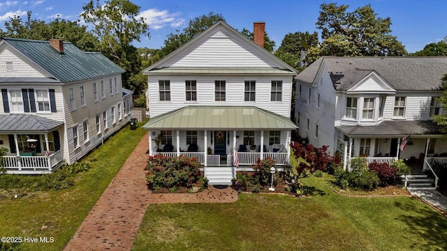 view of front of property featuring covered porch, a chimney, and a front lawn