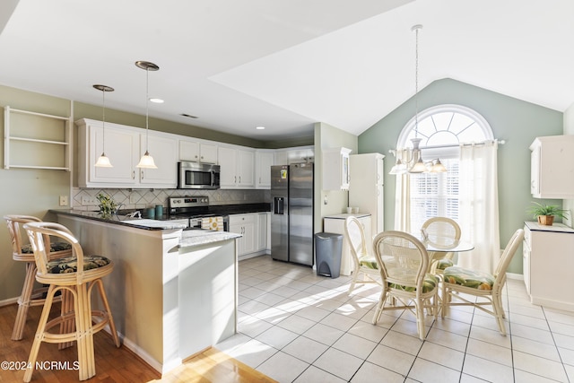 kitchen with a peninsula, white cabinetry, backsplash, hanging light fixtures, and stainless steel appliances