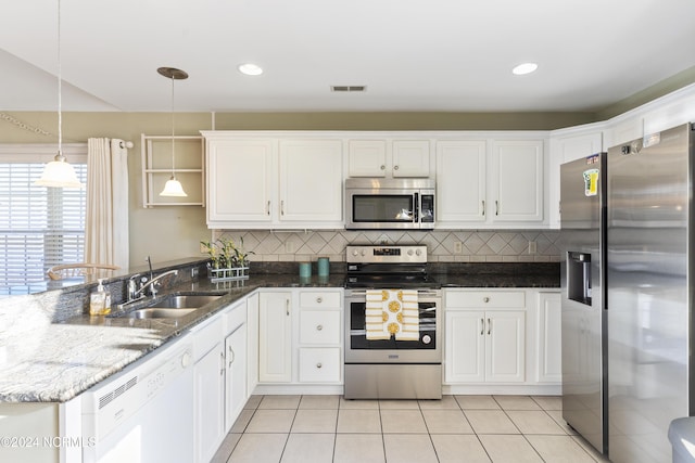 kitchen featuring appliances with stainless steel finishes, tasteful backsplash, a sink, white cabinets, and a peninsula