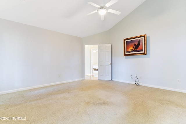 empty room with baseboards, ceiling fan, vaulted ceiling, and light colored carpet