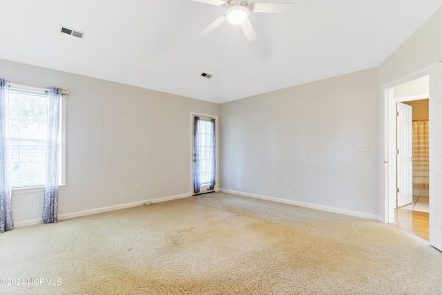 spare room featuring baseboards, light carpet, a ceiling fan, and visible vents