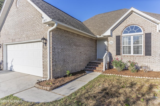 view of front of property with an attached garage, driveway, and brick siding