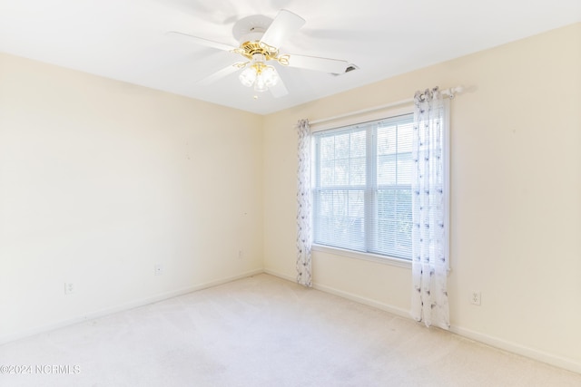 carpeted empty room with baseboards, visible vents, and ceiling fan