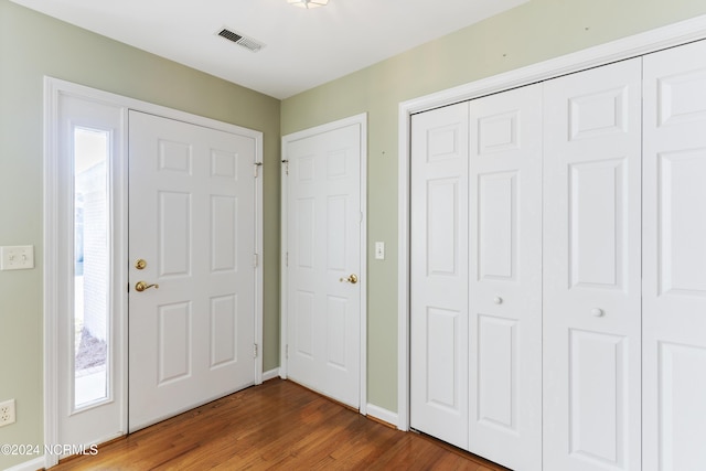 foyer with baseboards, wood finished floors, and visible vents