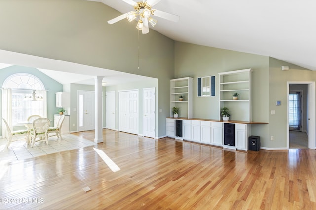 unfurnished living room with ornate columns, a ceiling fan, light wood-style floors, and high vaulted ceiling