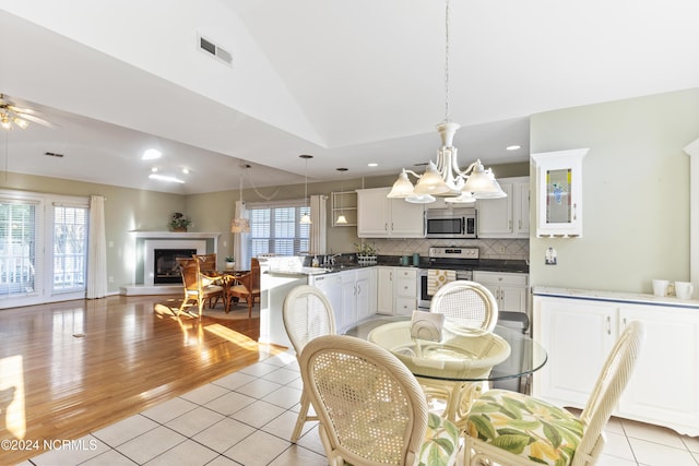 dining room featuring recessed lighting, a glass covered fireplace, light tile patterned floors, and vaulted ceiling